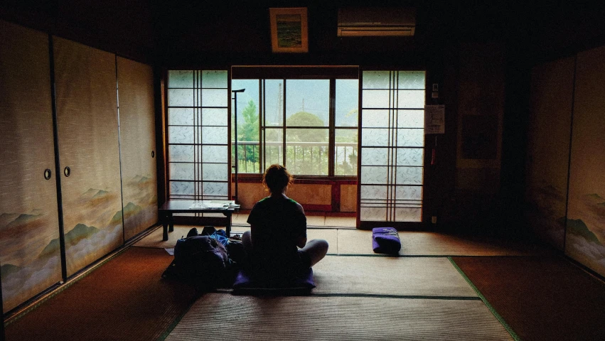 a person sitting on the floor in a room, inspired by Sesshū Tōyō, unsplash, 2000s photo, buddhist temple, window, sittin