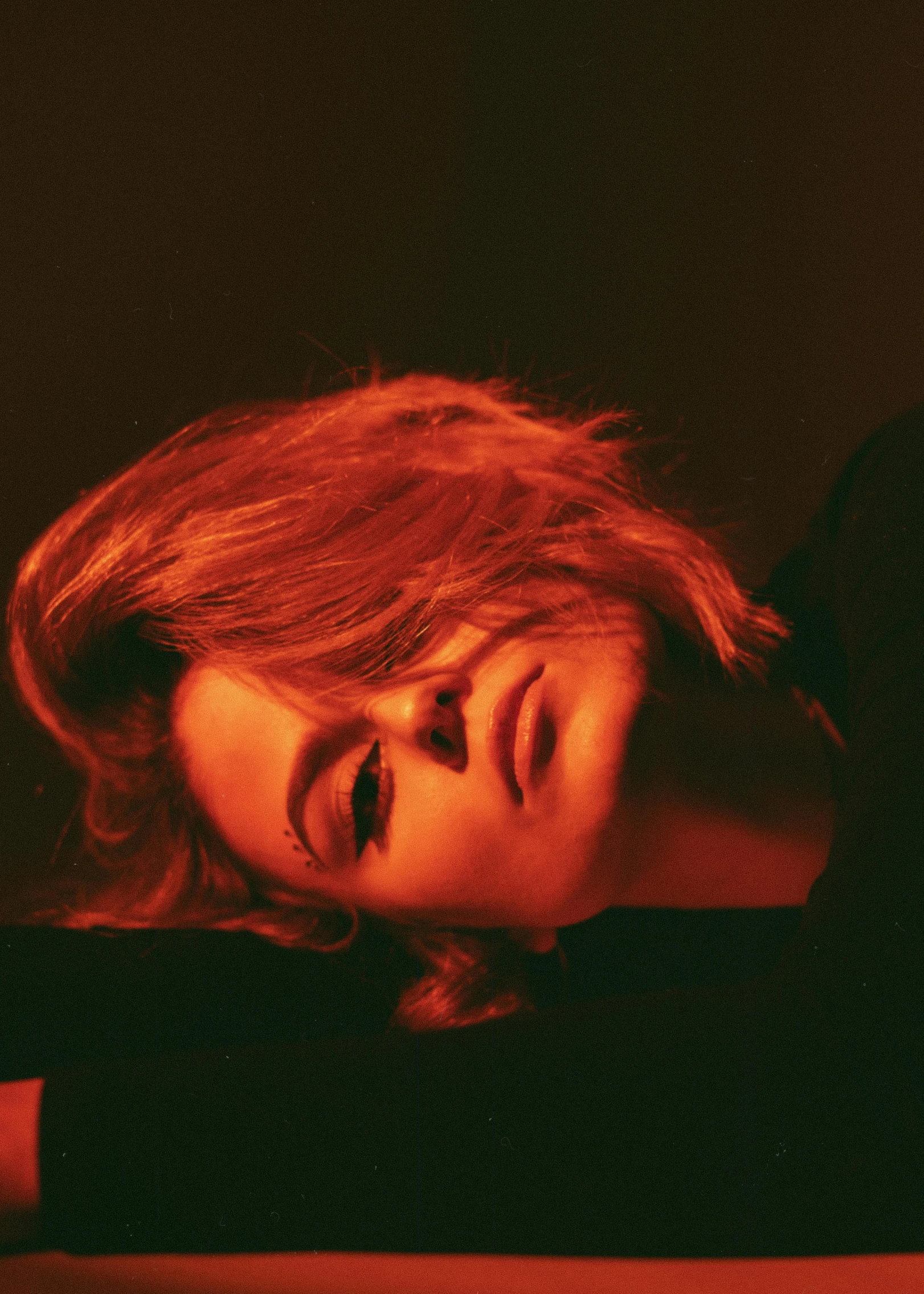 a woman laying on top of a bed under a red light, an album cover, inspired by Elsa Bleda, trending on pexels, evan rachel wood, profile portrait, maisie williams, infrared hair