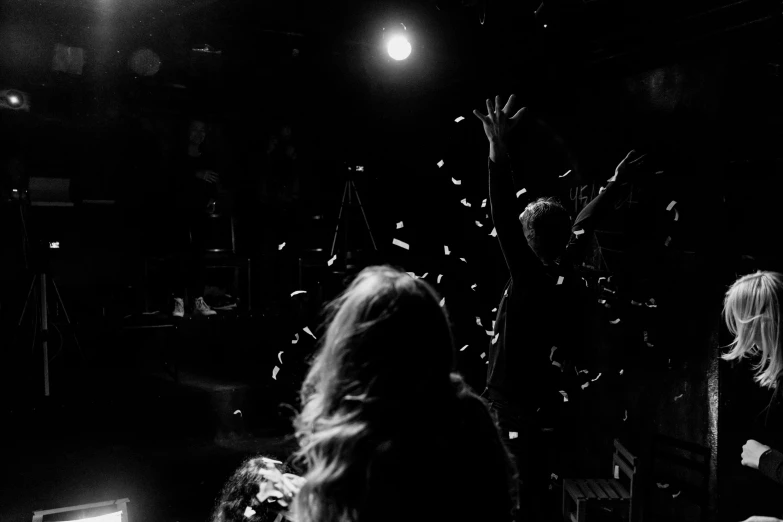 a group of people standing on top of a stage, a black and white photo, by Matija Jama, pexels contest winner, happening, falling petals, taken in night club, hands in her hair, [ shards