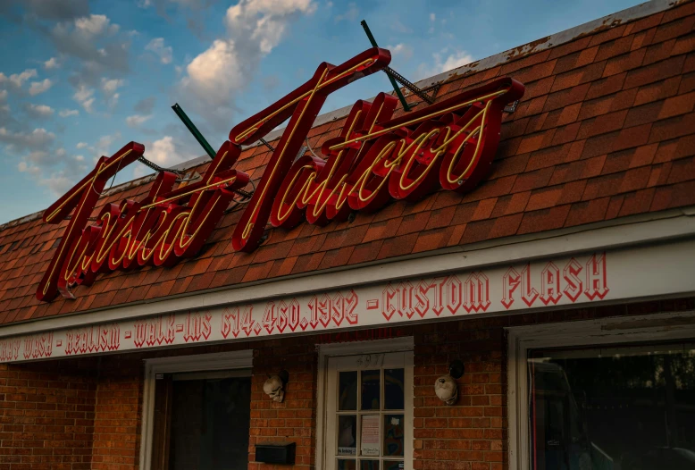 a sign that is on the side of a building, a tattoo, soft red lights, in style of cory loftis, fan favorite, smooth contours