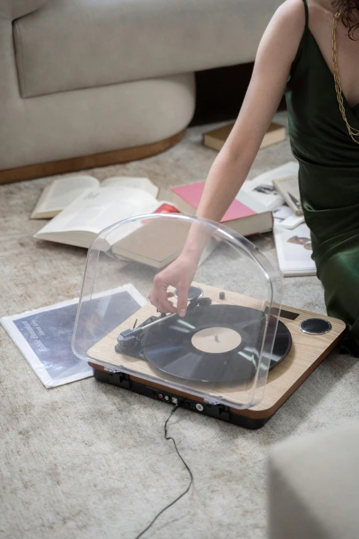 a woman sitting on the floor next to a record player, natural wood top, transparent, connectivity, zoomed in