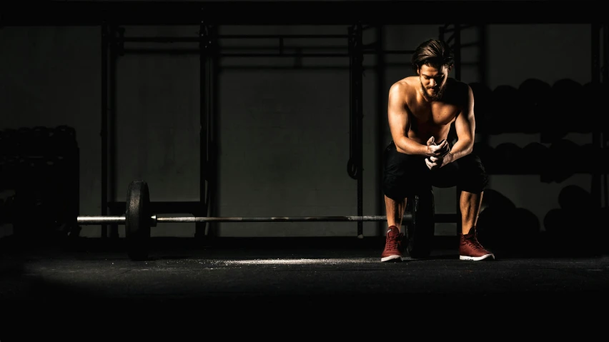 a man sitting on a bench in the dark, local gym, background image, scruffy man, thumbnail