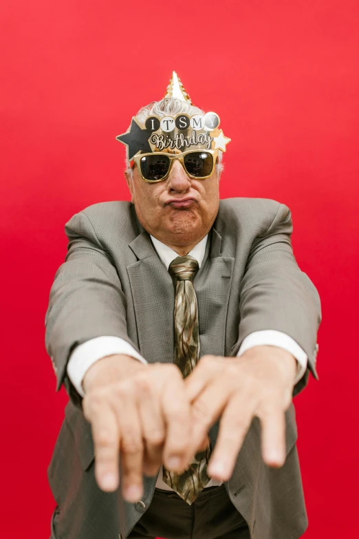 a man in a suit with a crown on his head, an album cover, inspired by Karl Matzek, unsplash, excessivism, danny devito, chrome mask, giving a thumbs up, grandfatherly