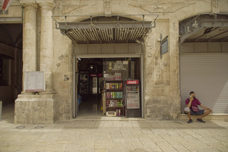 a man sitting on a bench in front of a book store, les nabis, nadav kander, conversano, exterior wide shot, 3 doors