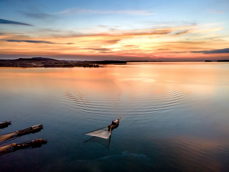 a person in a boat on a body of water, a picture, by Julian Allen, unsplash contest winner, floating robes, fish flying over head, bay area, sunset photo