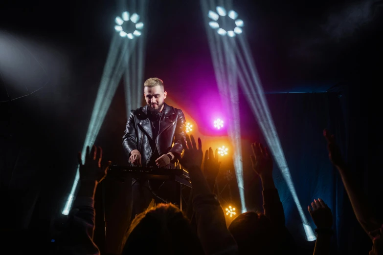 a man standing on top of a stage in front of a crowd, pexels, holography, singer maluma, wearing leather coat, avatar image, shining lights