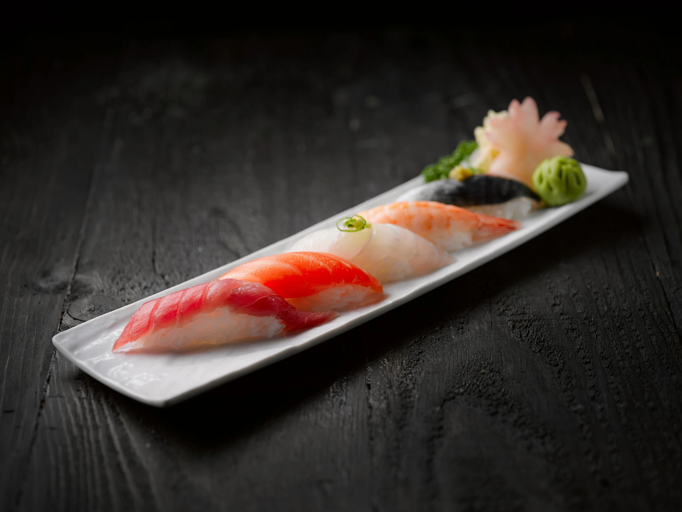 a white plate topped with sushi on top of a wooden table, 6 pack, sharp spines, 2 1 0 mm, 4yr old