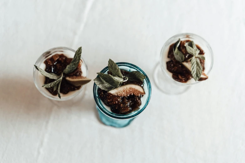 a couple of glasses filled with food on top of a table, by Carey Morris, unsplash, renaissance, fig leaves, desserts, sardine in a can, set against a white background