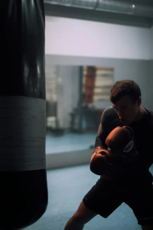 a man standing next to a punching bag, pexels contest winner, realism, in-game cinematic, natural lighting. 8 k, joe keery, grainy low quality
