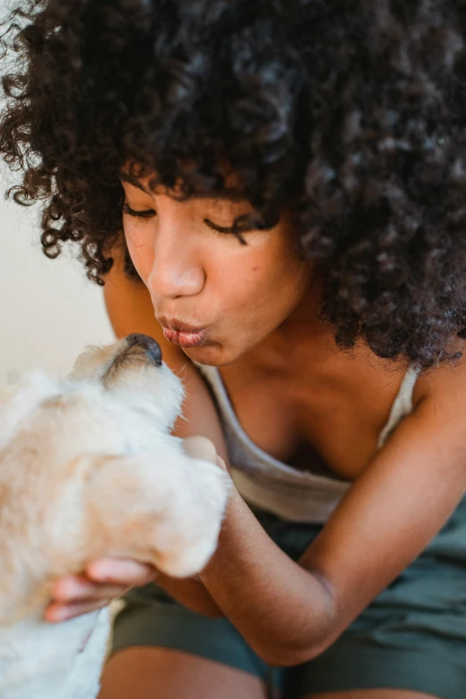 a woman kissing a teddy bear while sitting on a bed, a stock photo, trending on pexels, renaissance, breed corgi and doodle mix, photo of a black woman, cat and dog licking each other, portrait featured on unsplash