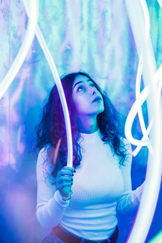 a woman holding a hula hoop in front of her face, inspired by David LaChapelle, trending on pexels, light and space, blue and purle lighting, lorde, emerging from her lamp, glowing tubes