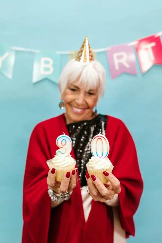 a woman holding two cupcakes with candles on them, a polaroid photo, trending on pexels, pop art, silver haired, party hats, aging, 9