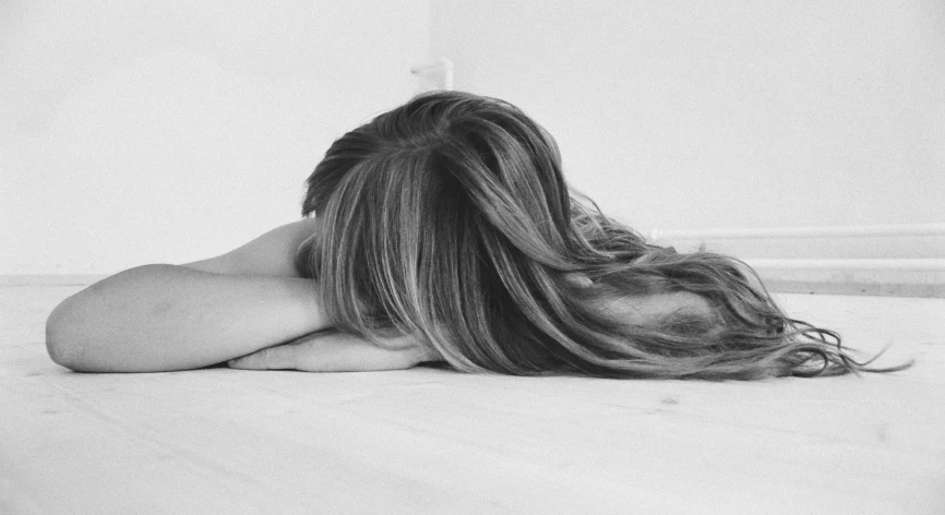 a black and white photo of a woman laying on the floor, a black and white photo, pixabay, hair down, on the bed, heartbroken, shoulder long hair