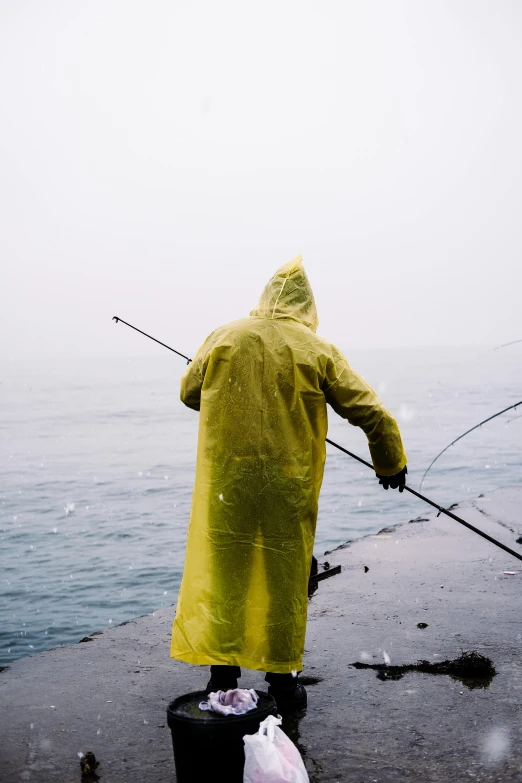 a man in a yellow raincoat is fishing, unsplash, gray, battered, instagram picture, taken in the late 2010s