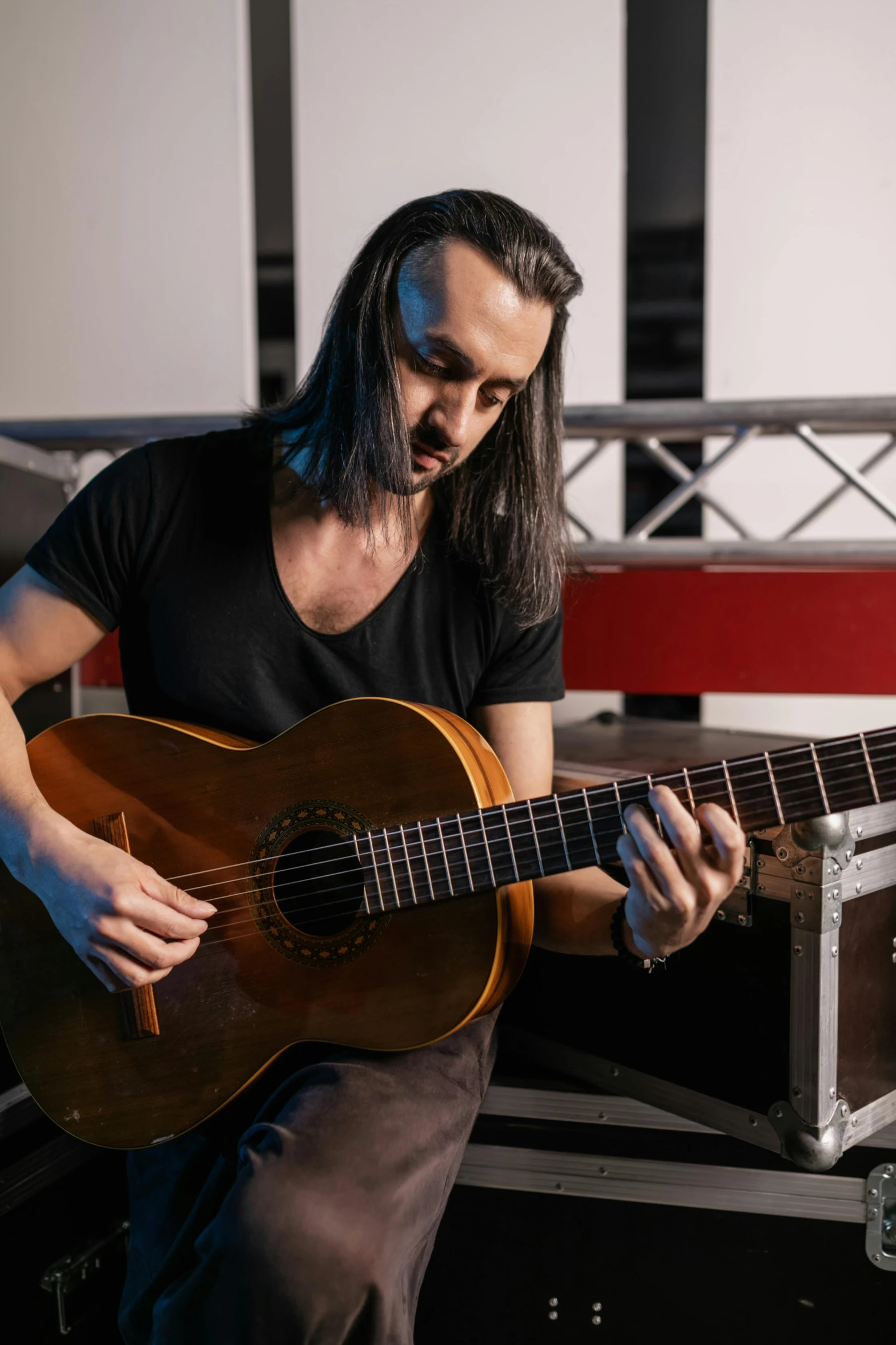 a man with long hair playing a guitar, antipodeans, looking off to the side, edin durmisevic, in a workshop, avatar image