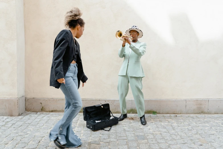 a woman standing next to a man playing a trumpet, by Emma Andijewska, pexels contest winner, figuration libre, jamel shabazz, wearing a light blue suit, stockholm, excitement