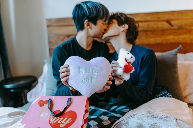 a couple of people that are sitting on a bed, a photo, by Julia Pishtar, pexels, holding gift, two men hugging, non-binary, cai xukun