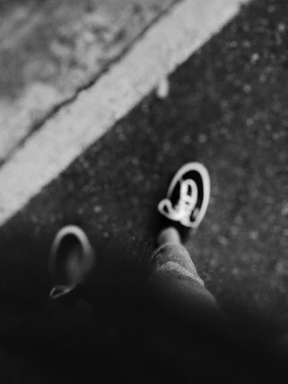 a black and white photo of a person's feet, by Emma Andijewska, unsplash, graffiti, toy camera, lonely rider, smiling down from above, swirly bokeh