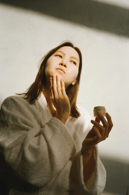 a woman standing in front of a mirror brushing her teeth, inspired by Elsa Bleda, unsplash, hyperrealism, wearing long white robe, kiko mizuhara, square facial structure, shot from below