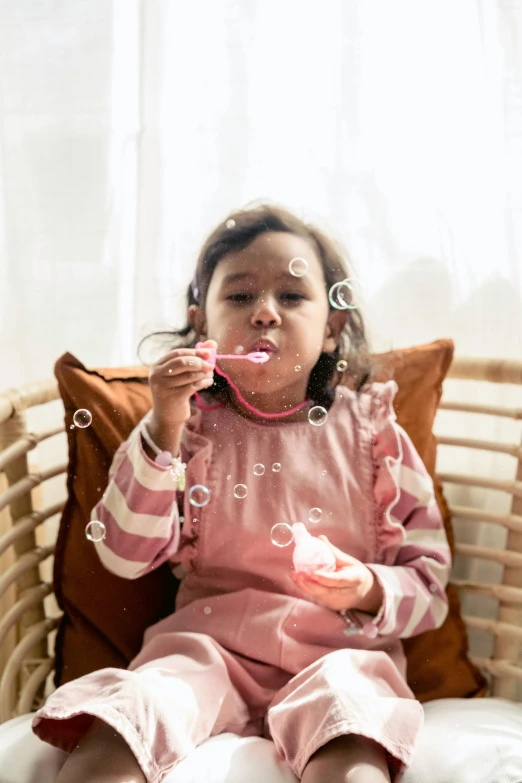 a little girl sitting on a chair blowing bubbles, pexels contest winner, hurufiyya, mouth slightly open, resin, promotional image, puff sleeves