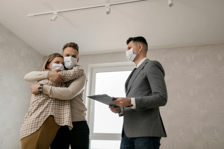 a man and woman hug each other while wearing masks, a photo, an estate agent listing photo, leaving a room, healthcare, brown