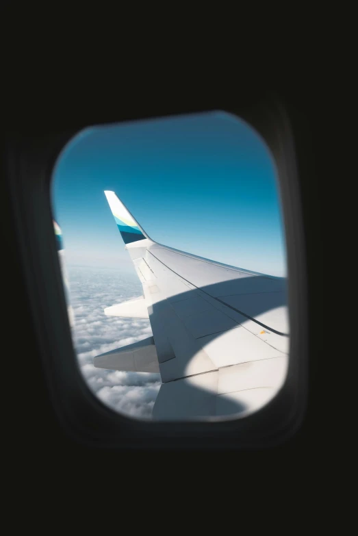 a view of the wing of an airplane through a window, pexels contest winner, brown and cyan blue color scheme, gazing off into the horizon, waving, high-angle