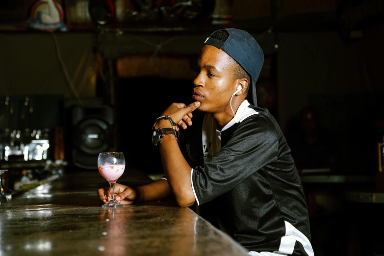 a woman sitting at a bar with a glass of wine, a portrait, unsplash, renaissance, black teenage boy, androgynous male, 2000s photo, shot on sony a 7