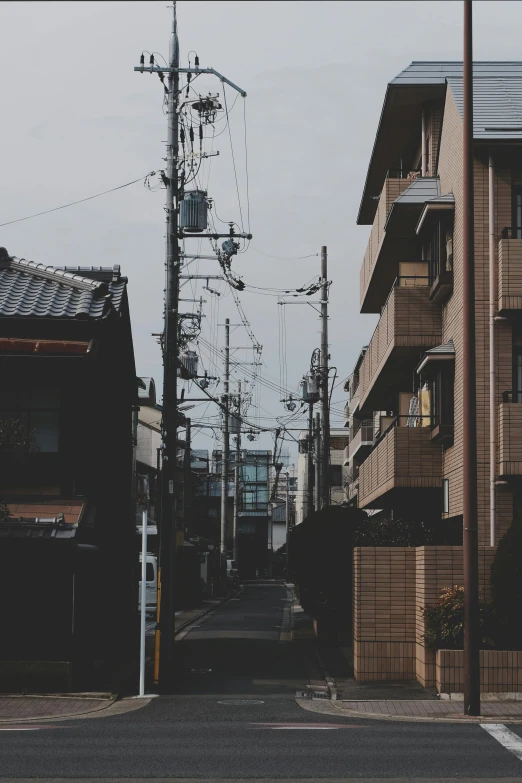 a couple of tall buildings sitting on the side of a road, by Sengai, unsplash, attached to wires. dark, japanese rural town, telephone pole, low quality photo