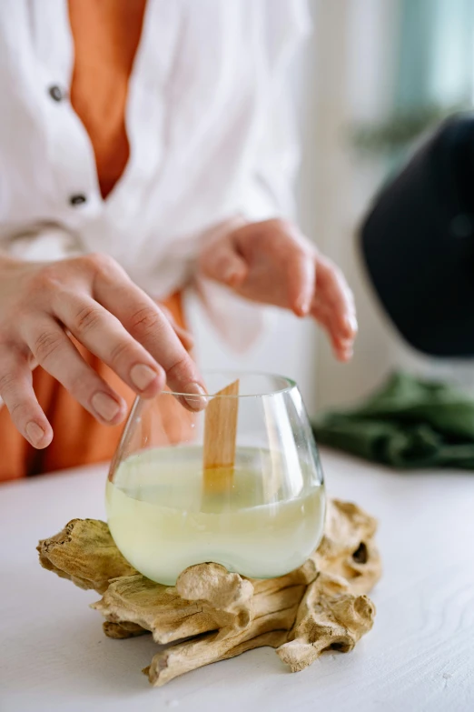 a close up of a person putting something in a bowl, inspired by Kanō Shōsenin, renaissance, white candles dripping wax, lemonade, wine glass, holding a wood piece