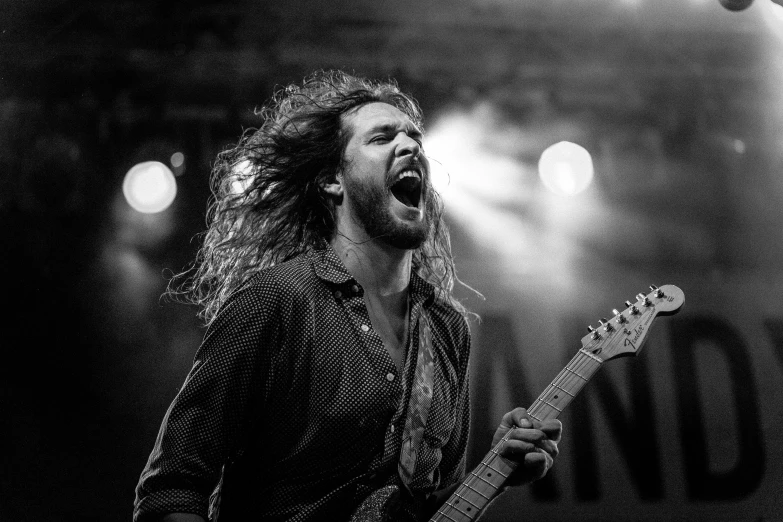 a man with long hair playing a guitar, a black and white photo, by Mathias Kollros, pexels contest winner, man screaming, stoner rock concert, a photo of a disheveled man, wind in hair