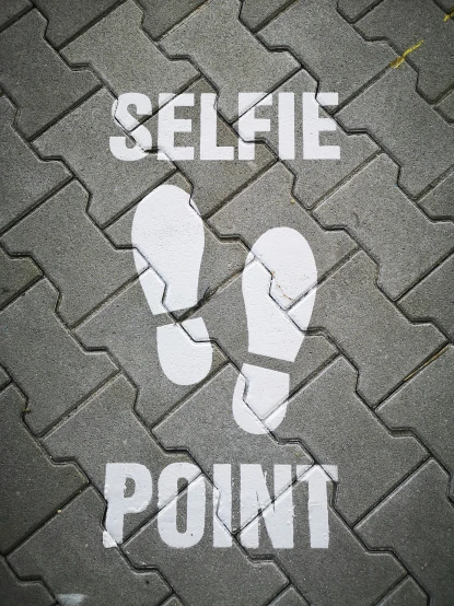 a sign that says selfie point on a sidewalk, an album cover, inspired by Vivian Maier, shutterstock, graffiti, grey, serrated point, tyre mark, set on singaporean aesthetic