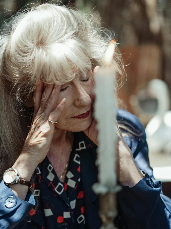 a woman sitting at a table with a candle, a portrait, trending on pexels, a silver haired mad, facepalm, wrinkly forehead, tall