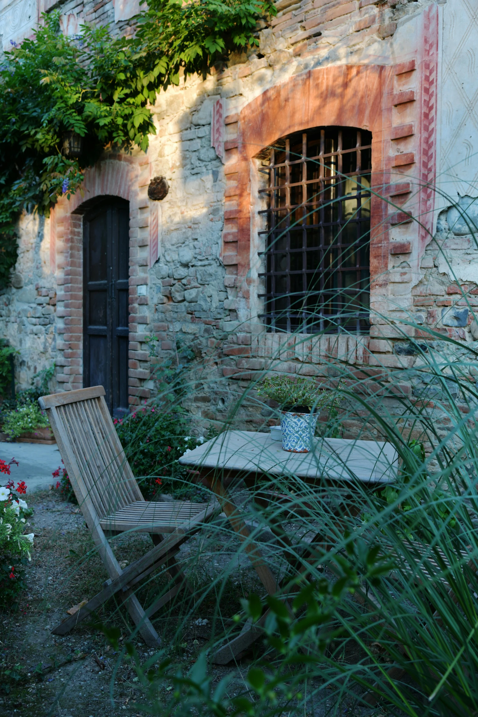 a wooden chair sitting in front of a brick building, renaissance, lush garden surroundings, sienna, cosy