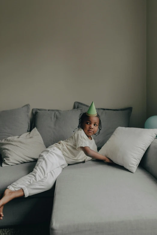a little girl laying on a couch wearing a party hat, inspired by Maurice Sendak, pexels contest winner, black teenage boy, cinematic full shot, toddler, slightly minimal
