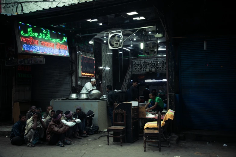 a group of people sitting outside of a restaurant, by Ahmed Yacoubi, hurufiyya, neon shops, inside a tavern, nadav kander, small manufacture