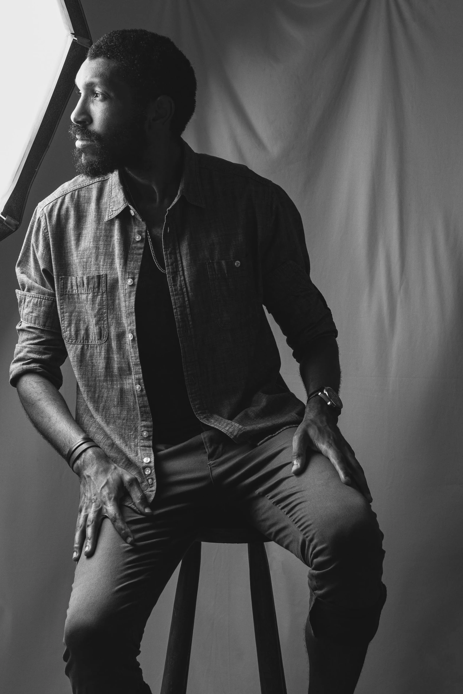 a black and white photo of a man sitting on a stool, pexels contest winner, a portrait of rahul kohli, hands in pockets, lumberjack, profile picture 1024px