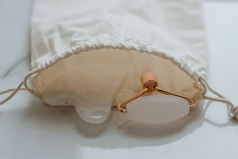 a white bag sitting on top of a white table, clamp shell lighting, hibernation capsule close-up, ivory and copper, filling with water