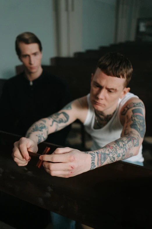 two men sitting next to each other at a table, a tattoo, pexels, bauhaus, in a church. arstation, yung lean, promotional image, hammershøi