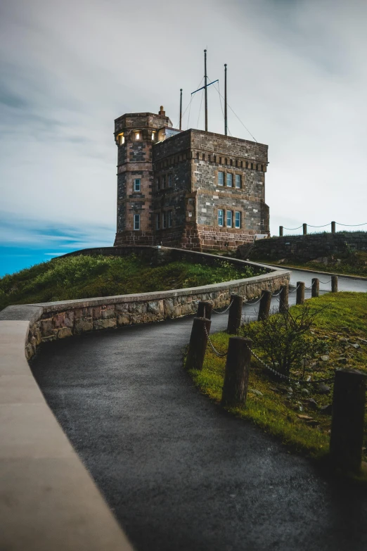 a stone building sitting on top of a lush green hillside, by Jesper Knudsen, pexels contest winner, elegant walkways between towers, rhode island, moody setting, wellington