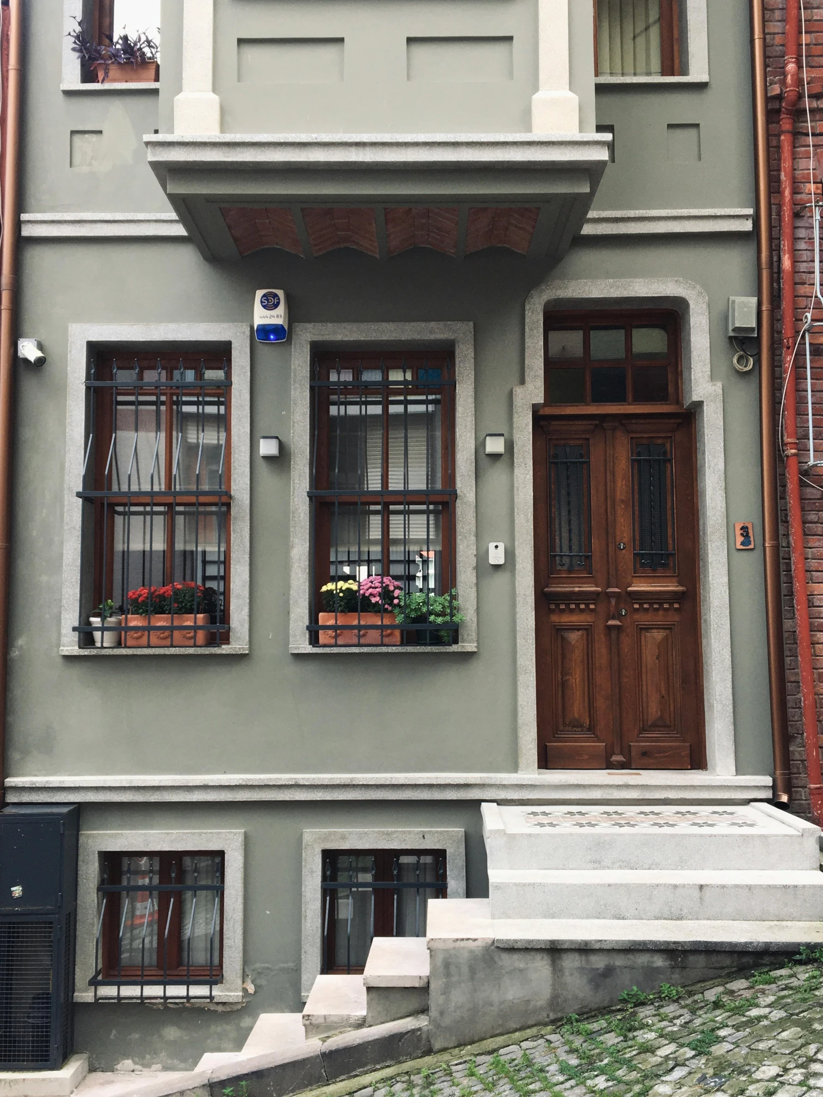 a building with a clock on the front of it, inspired by Niyazi Selimoglu, small path up to door, very comfy], completely new, desaturated!