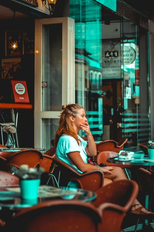 a woman sitting at a table outside of a restaurant, pexels contest winner, brown and cyan color scheme, android coffee shop, looking off into the distance, teenage girl