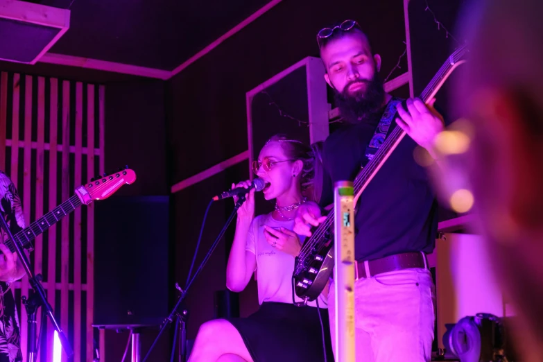 a group of people standing next to each other on a stage, pexels, antipodeans, playing guitar onstage, closed limbo room, purple glow, profile image