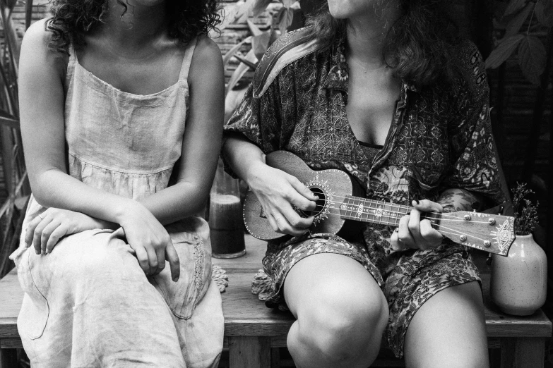 a couple of women sitting on top of a wooden bench, a black and white photo, by Maurycy Gottlieb, pexels, ukulele, justina blakeney, sing with me, mamou - mani