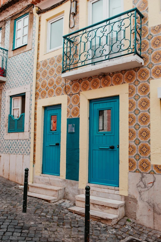 a couple of blue doors sitting on the side of a building, inspired by Almada Negreiros, tiles, multicolor