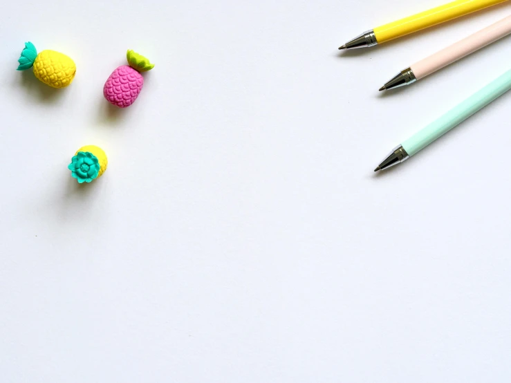 a group of pencils sitting on top of a white table, colorful adornments, pen on white paper, pink and yellow, modeled