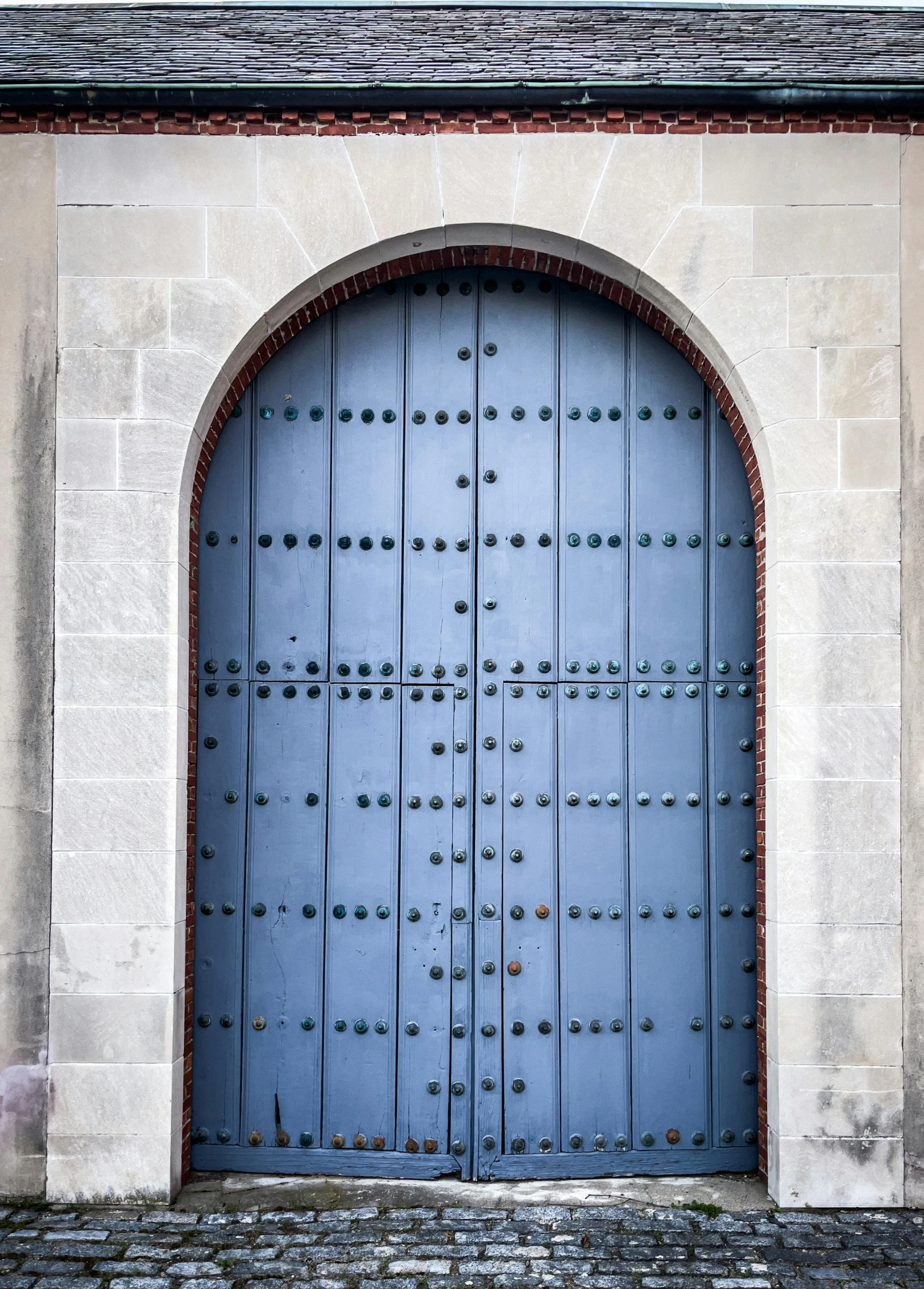 a blue door that is on the side of a building, inspired by Luis Paret y Alcazar, unsplash, steel archways, square, grey, rivets