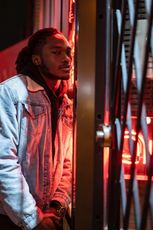 a man standing in the doorway of a building, an album cover, trending on pexels, red neon lights, looking serious, reflective puffer jacket, standing in a server room