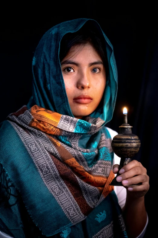 a woman holding a lit candle in her hand, a colorized photo, inspired by Steve McCurry, head scarf, 8k award-winning photograph, wearing traditional garb, 2019 trending photo