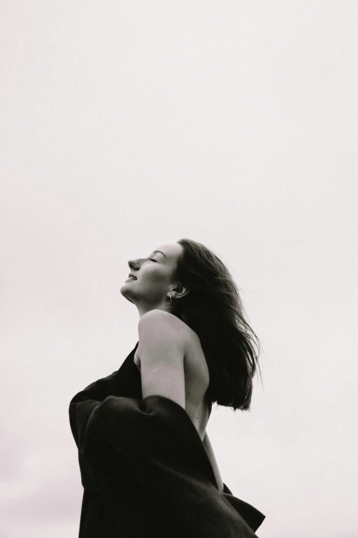 a black and white photo of a woman in a dress, unsplash, happening, bright sky, emily blunt, head bent back in laughter, cloaked woman