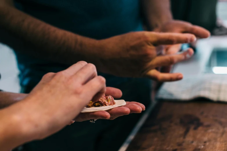 a group of people sitting at a table eating food, by Lee Loughridge, pexels contest winner, closeup of a butcher working, holds a small knife in hand, lachlan bailey, hands which exchange seeds